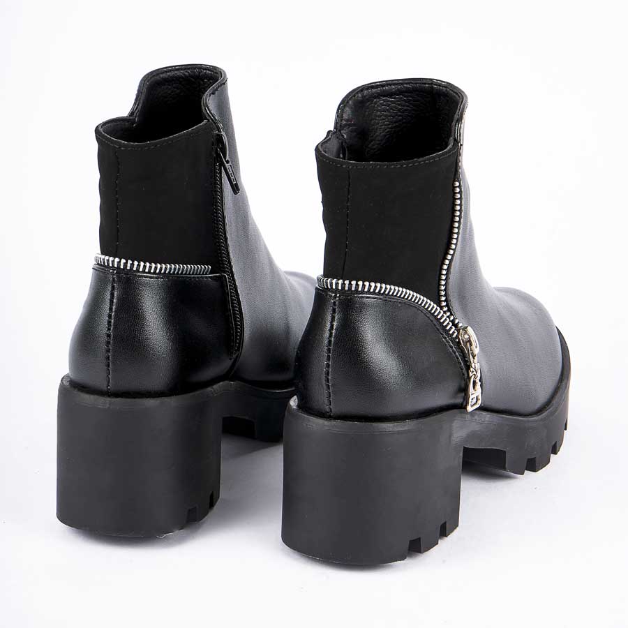 Botines para dama 235, de color negro. Están fabricados en cuero sintético, son de caña baja y tacón bajito. Y tienen accesorios plateados como herrajes y cierre.Los zapatos se ven desde atrás y puestos sobre un fondo blanco.