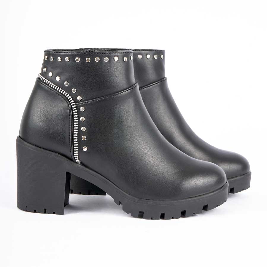 Botines para dama 262, de color negro. Están fabricados en cuero sintético, son de caña media y tacón medio. Y tienen accesorios plateados como taches, herrajes y cierre.Los zapatos están de perfil y puestos sobre un fondo blanco.