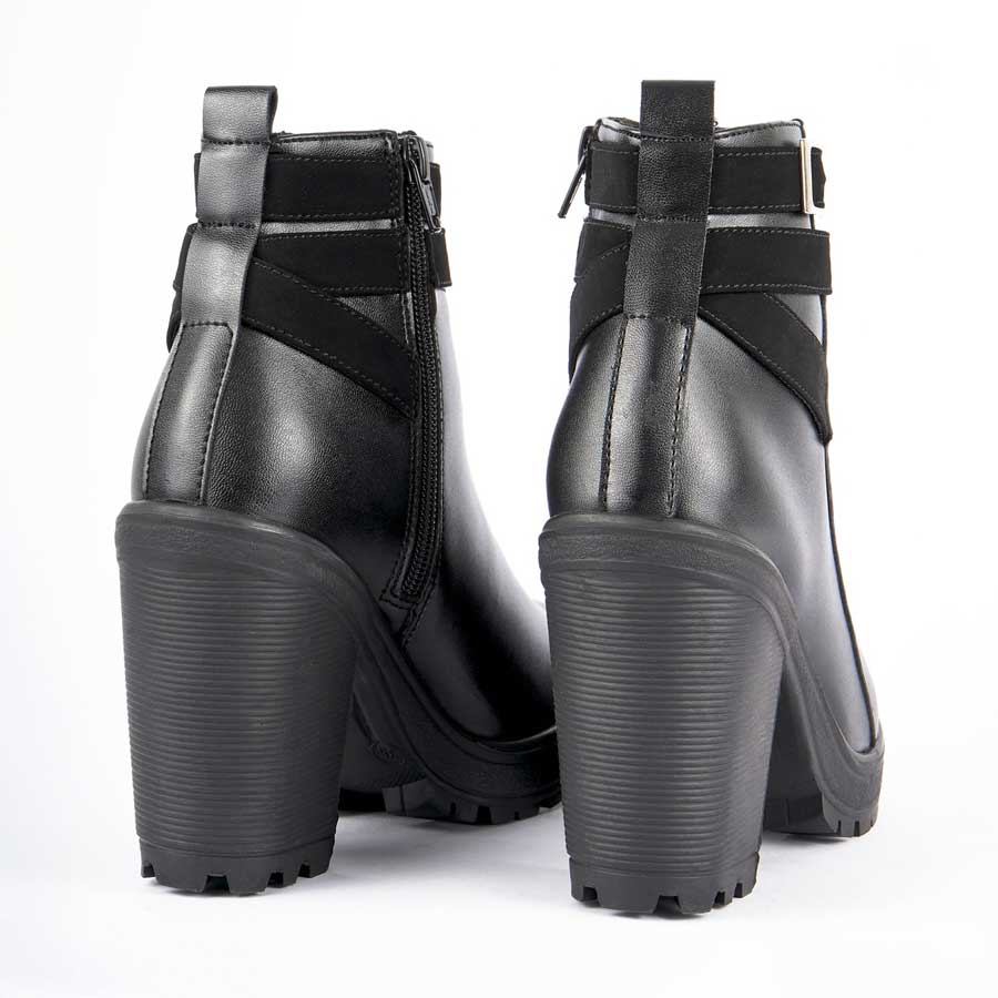 Botines para dama 286, de color negro. Están fabricados en cuero sintético, son de caña media y tacón alto. Y tienen accesorios como correas y cierre.. Los zapatos se ven desde atrás y puestos sobre un fondo blanco.