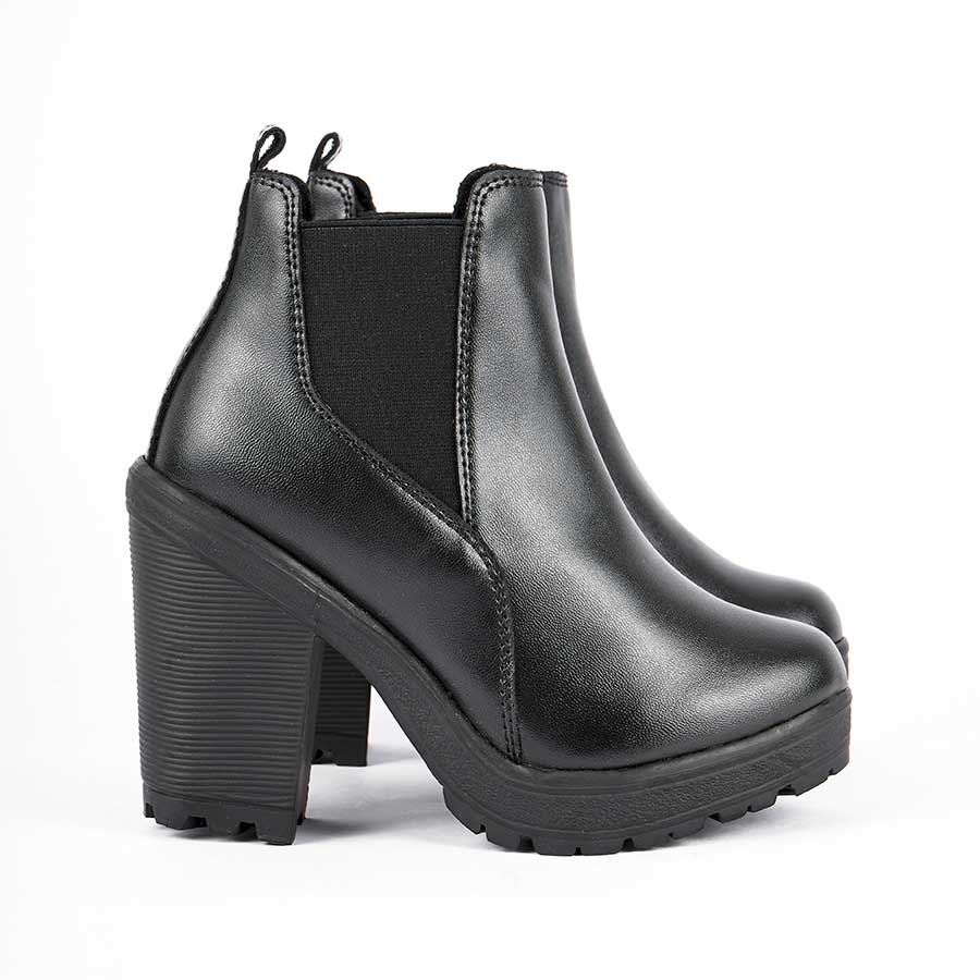 Botines para dama sandy, de color negro. Están fabricados en cuero sintético, son de caña media y tacón alto. Y elásticos en los laterales.Los zapatos están de perfil y puestos sobre un fondo blanco.