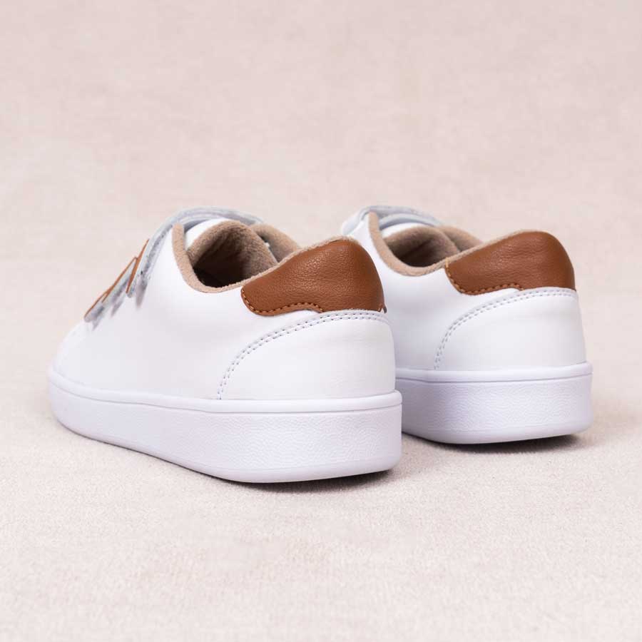 Tenis blancos para dama noa. Están fabricados en cuero sintético, son de plataforma. Y tienen accesorios plateados como  correas Los zapatos se ven desde atrás y puestos sobre un fondo blanco.